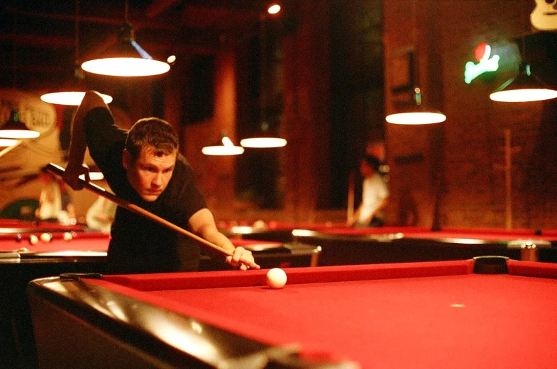 man about to hit a pool ball in a dark room