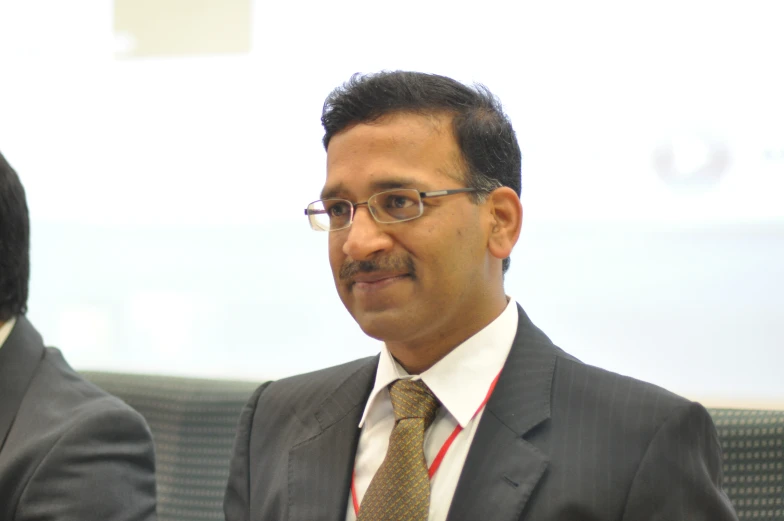 a man with glasses and suit jacket and tie