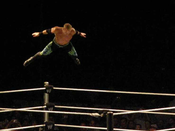 the man is jumping over the ropes on his wrestling team