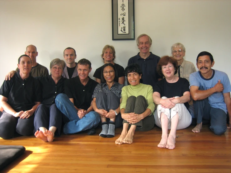 a large group of people in black shirts posing on wooden floors