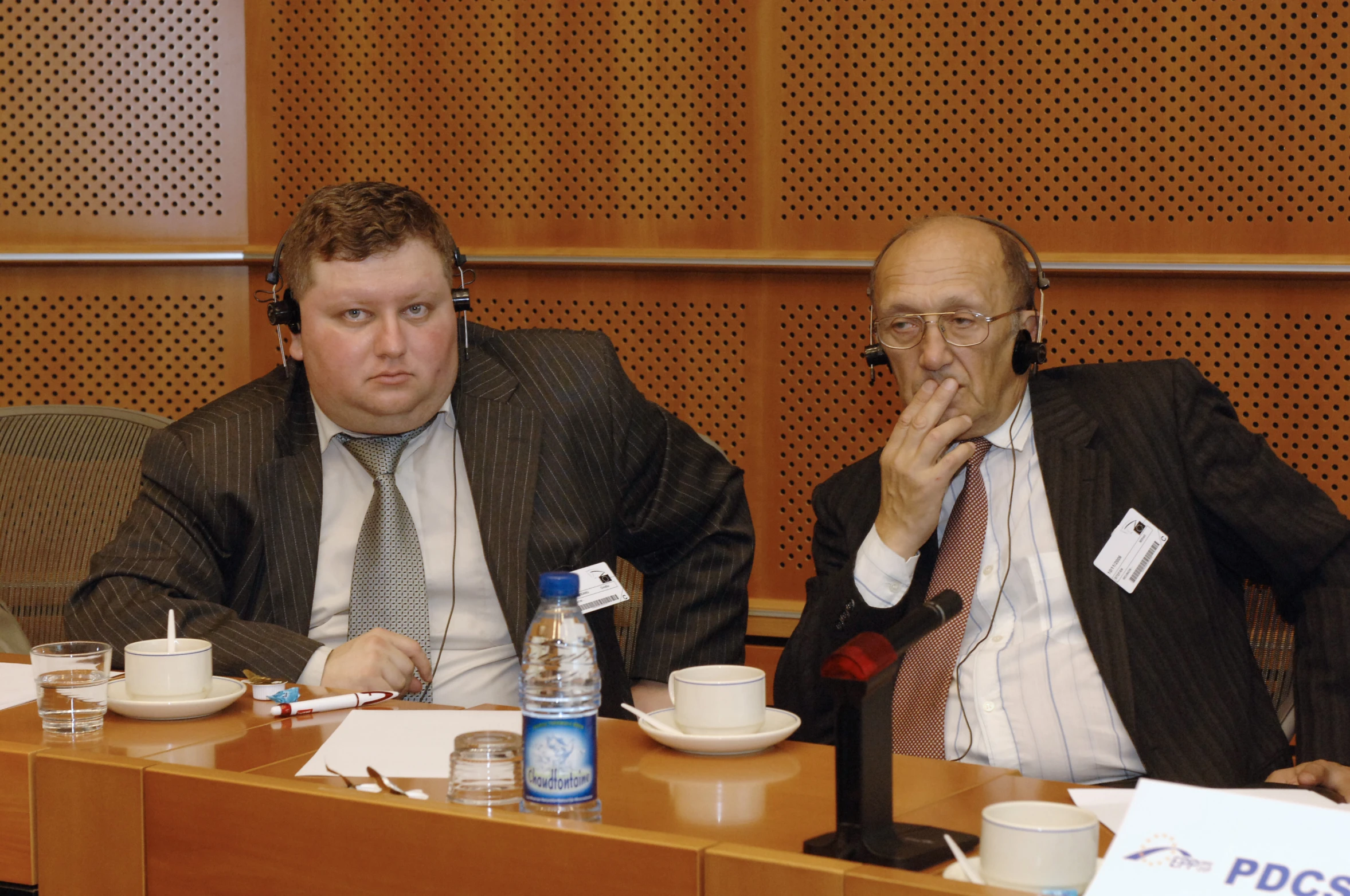 two men sit at a table with tea and other drinks in front of them