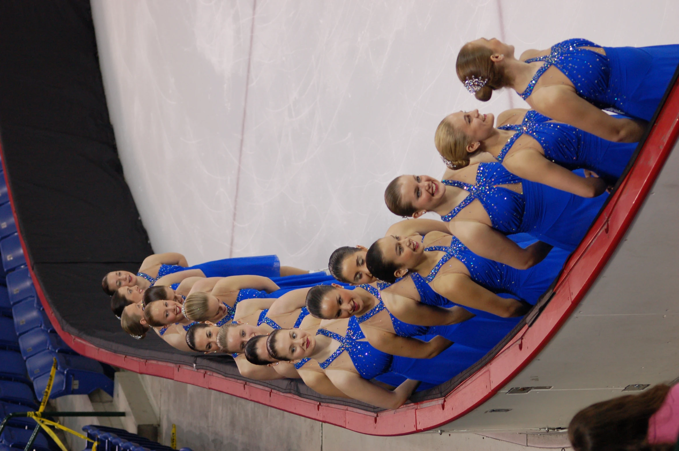 a group of women in blue dresses standing on an ice rink