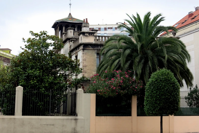 a tall building is near the wall and trees