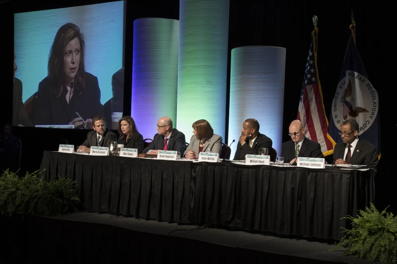 people sitting around a table with microphones at a debate