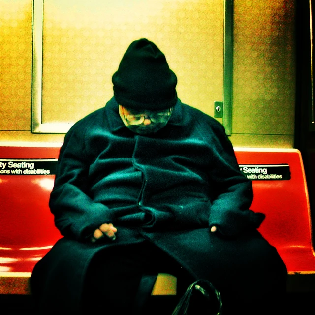 an old woman in winter clothes is sitting on the bus