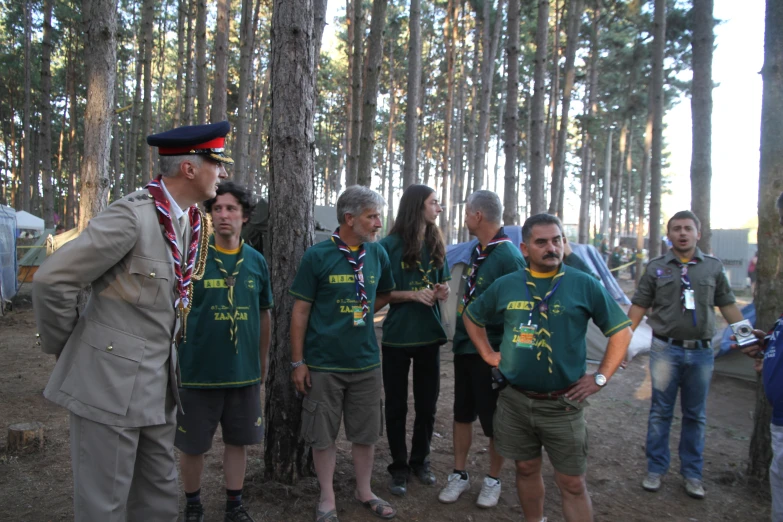 men in green shirts stand in a forest with trees