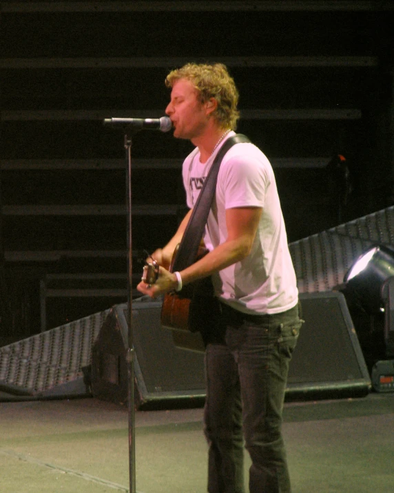 a man with a guitar stands next to a microphone