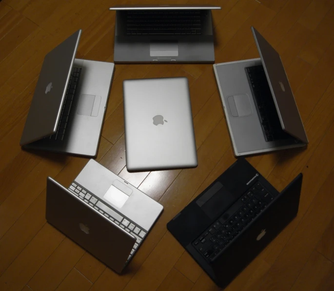 a group of five apple laptop computers are on the table