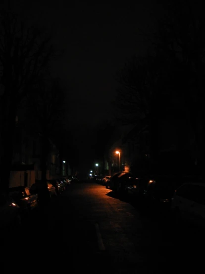 a street at night with a few cars parked