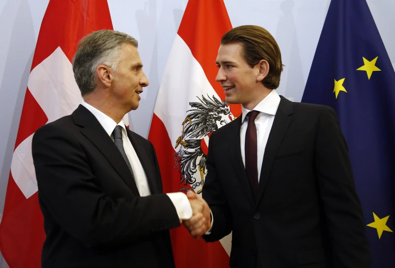 two men shaking hands in front of flags