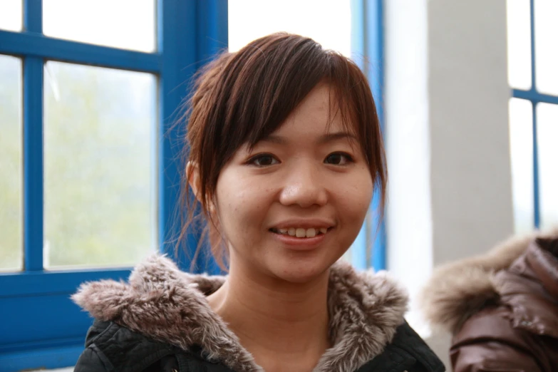 a woman standing in front of windows smiling for the camera