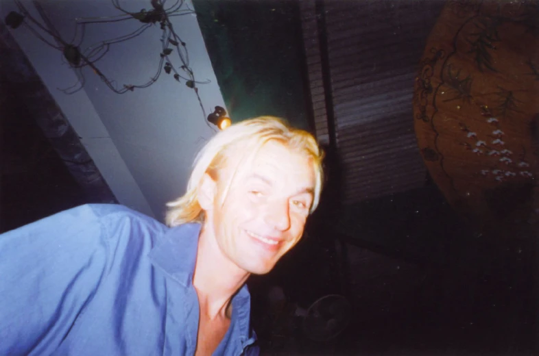 a young man is smiling while sitting near a hanging vase