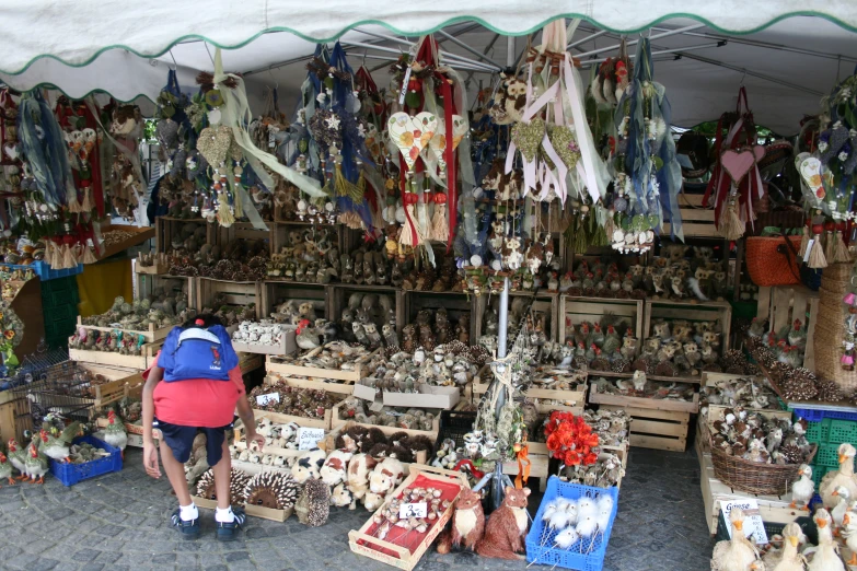 a vendor standing next to an outside market with lots of souvenirs