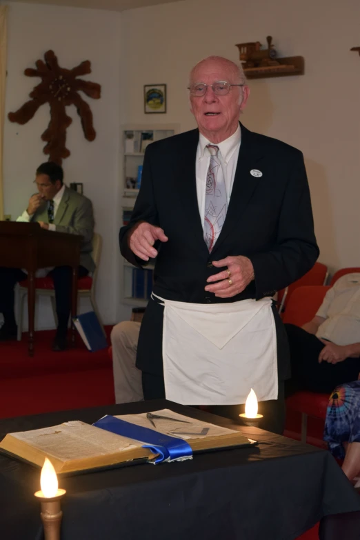 a man who is wearing an apron standing next to an open book