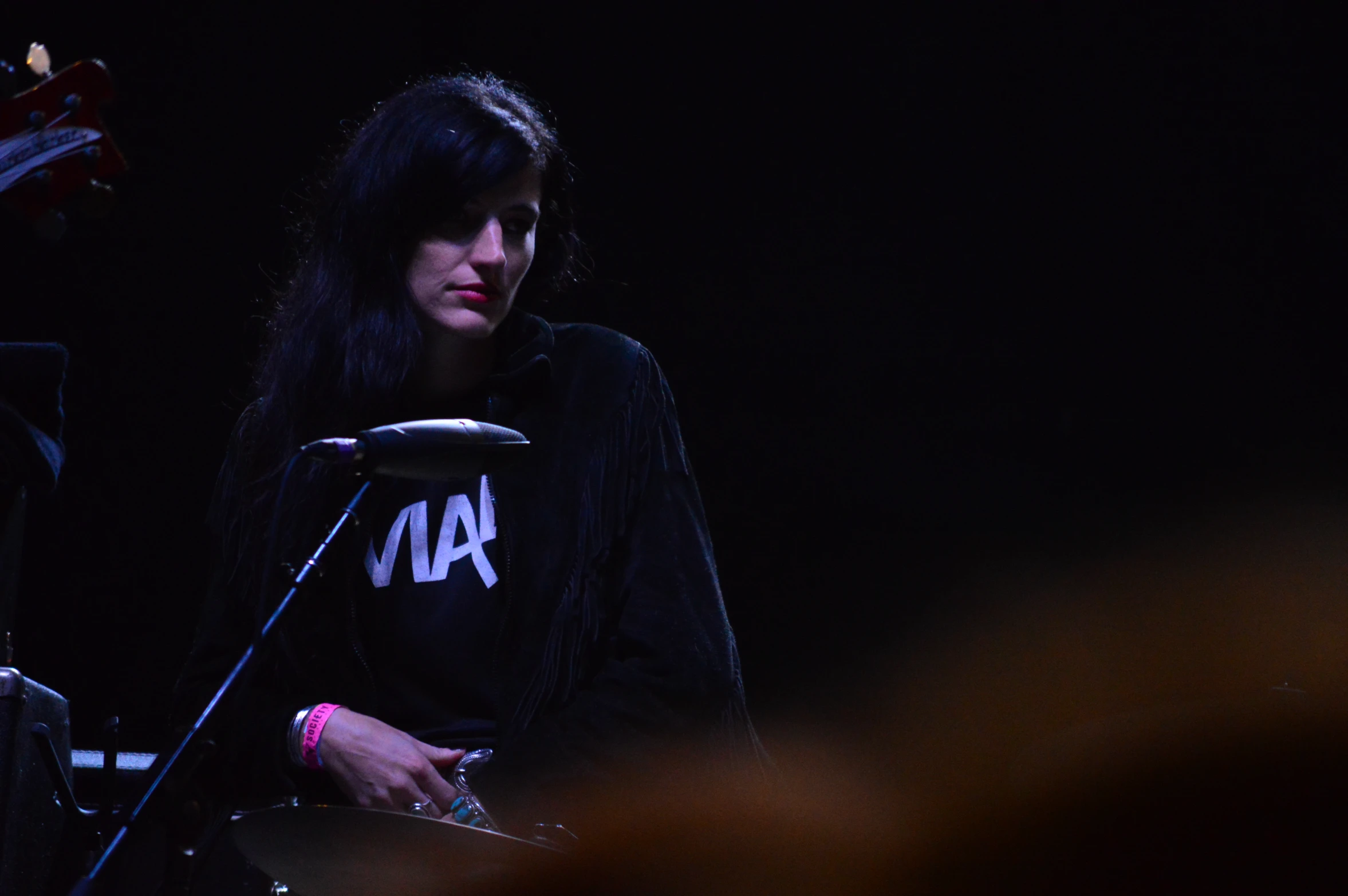 woman with long black hair playing guitar on stage