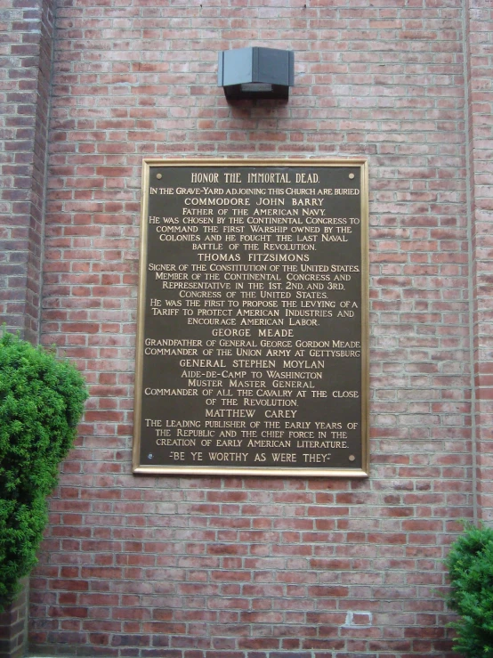 a large plaque sitting against a brick building