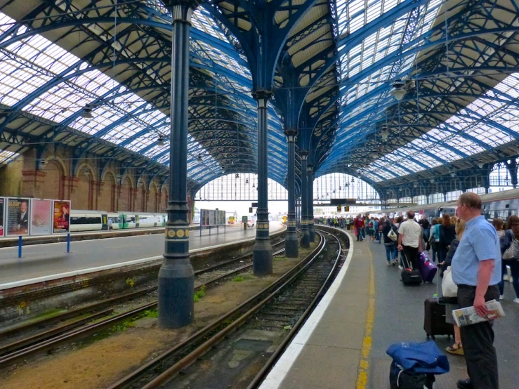 a crowded train station with blue skylights and lots of people