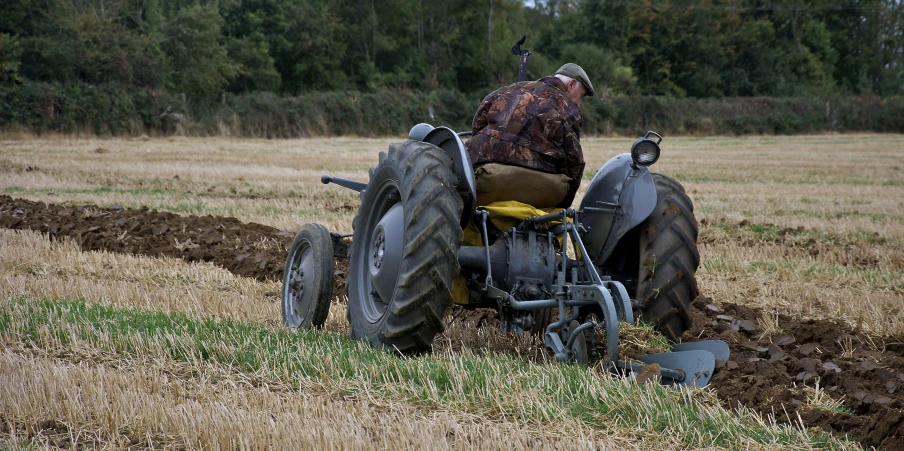 an old tractor parked in a field filled with mud