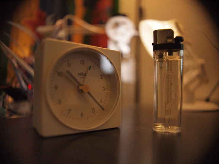 a clock on a table beside a small plastic tube