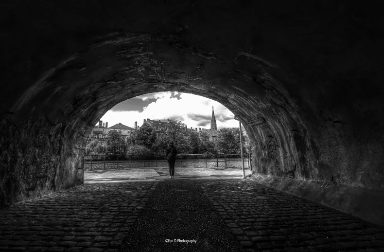 a person walking in front of a large tunnel