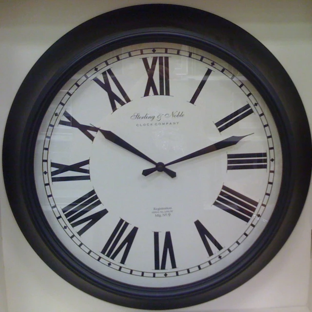 a black and white clock with roman numerals is on the wall