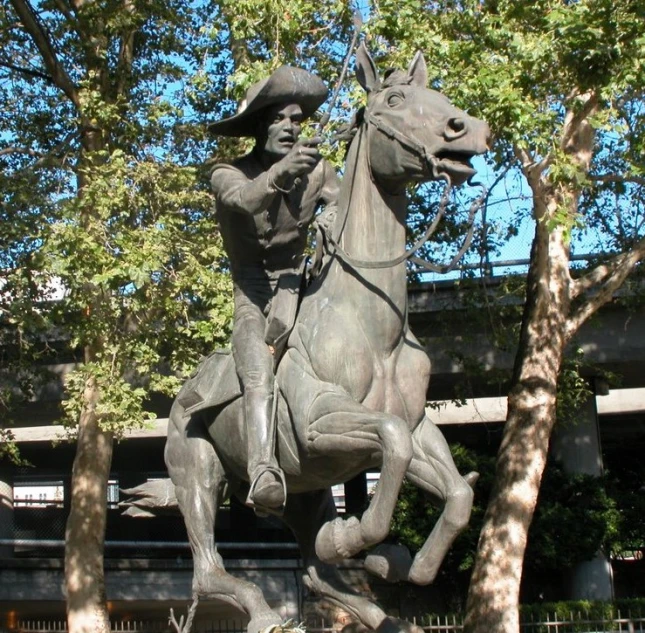 a statue of a man on horseback that is sitting by a tree