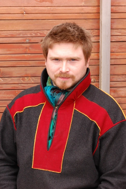 a young man wearing a red, brown, and black coat and scarf