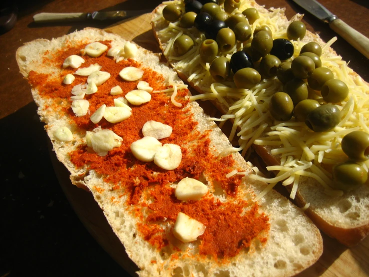 some food on bread, and some olives on a table