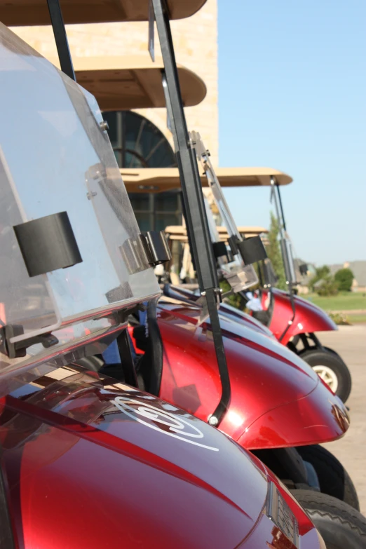 the side view of several red, four wheeled golf carts