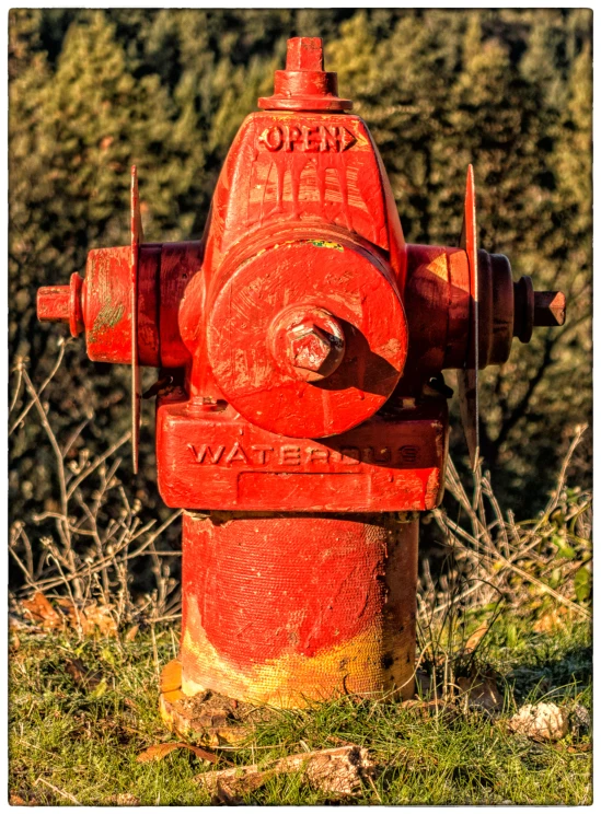 an old red fire hydrant sitting in the grass