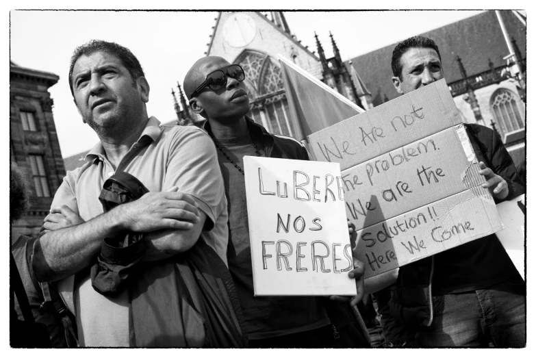 people holding up signs outside and wearing sunglasses