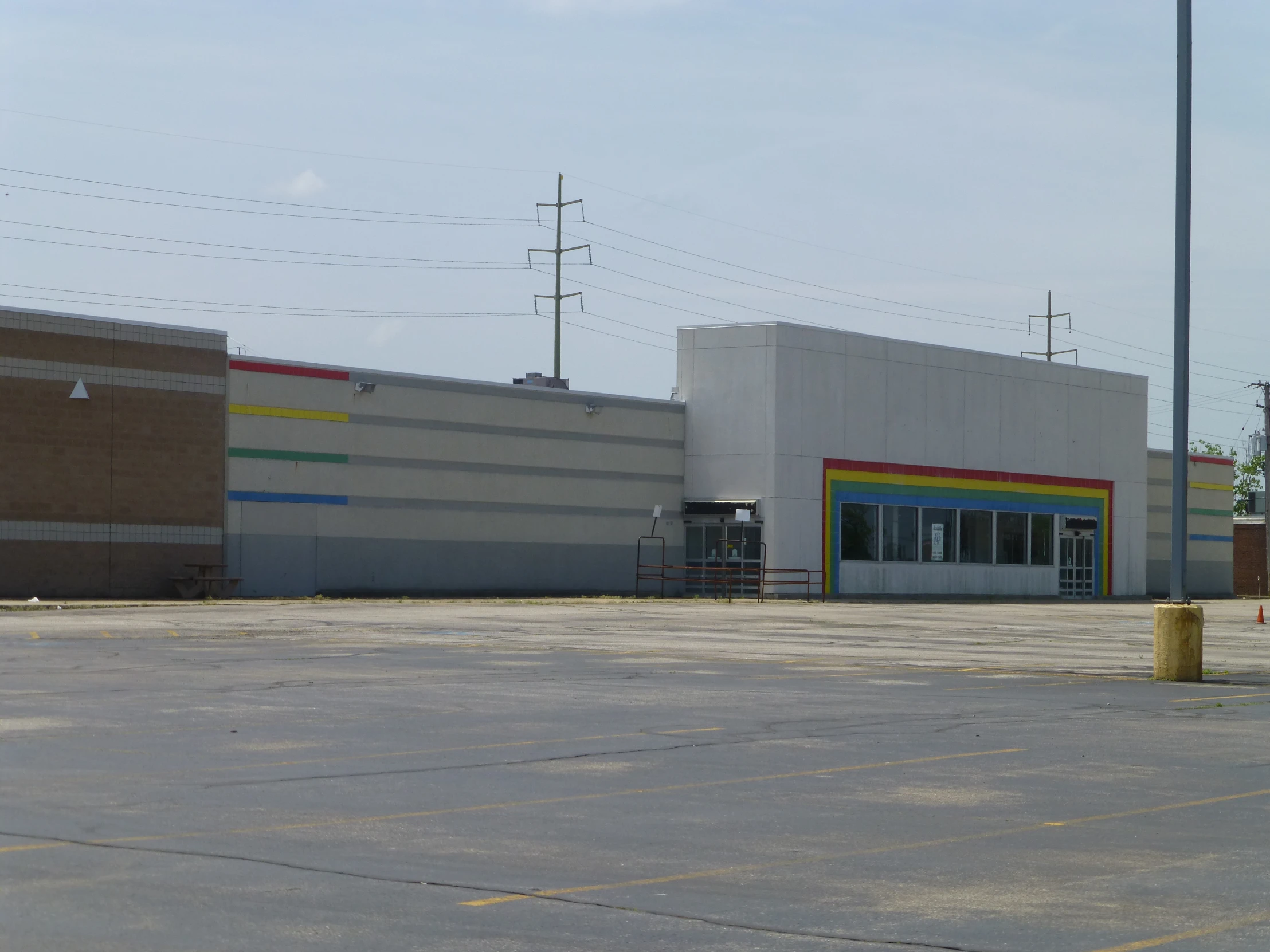 an empty parking lot and building with some poles and power lines