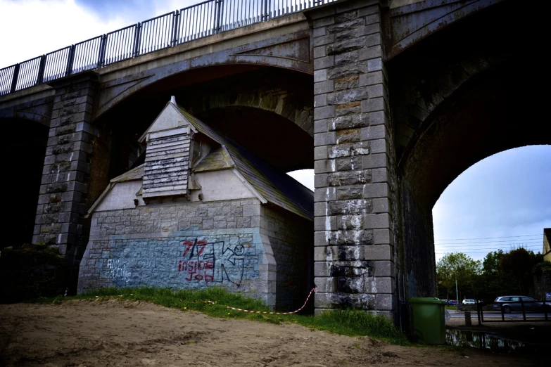 a small bridge sitting next to another bridge with graffiti on it