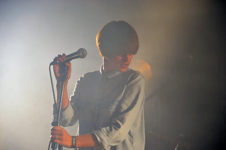 a young man holding a microphone in his right hand