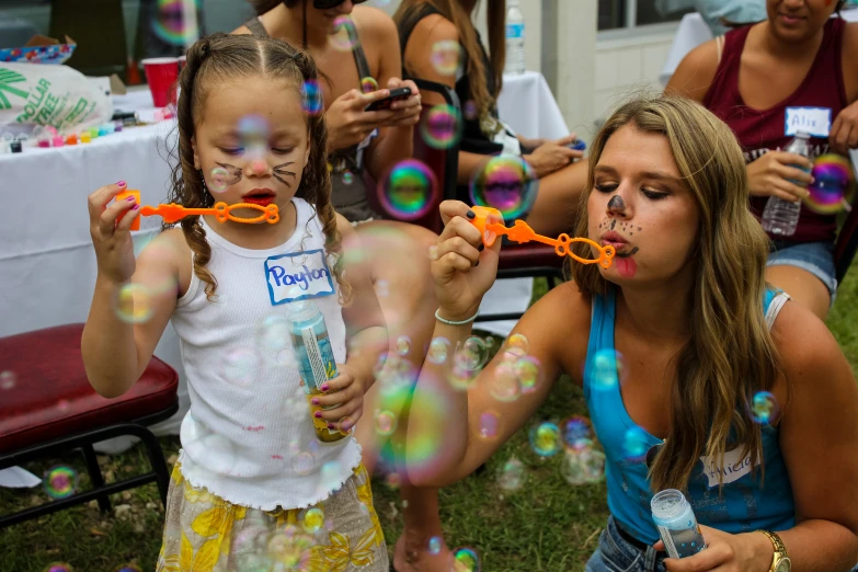 the little girls are playing with bubbles with their mom