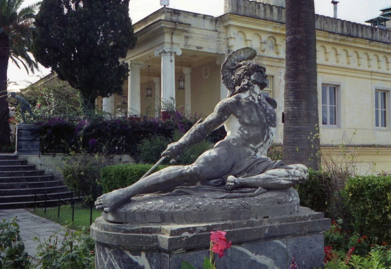 a sculpture sitting outside on the ground in front of some flowers