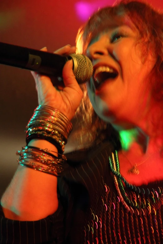 the woman is singing on stage and holding a microphone in her hand