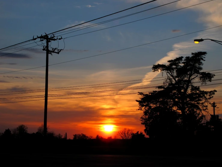 the sun rises in the sky with power lines above it