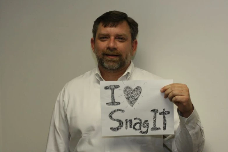 a man holds up a sign and smiles at the camera