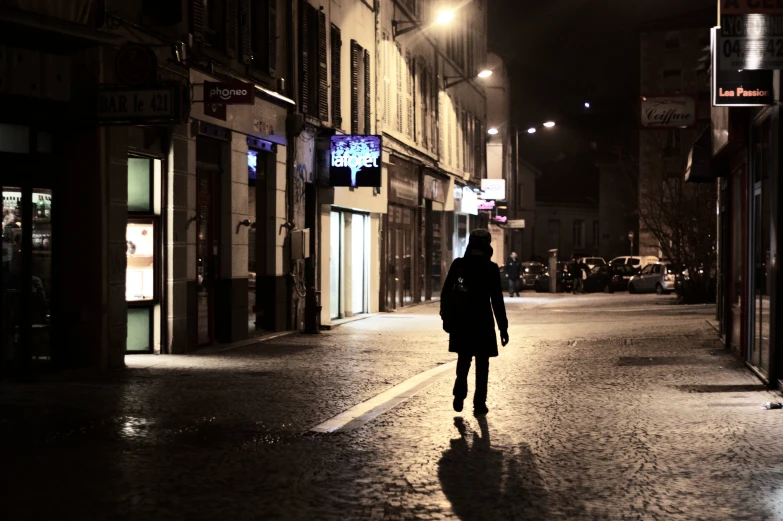 a person walking down a street at night with lights on