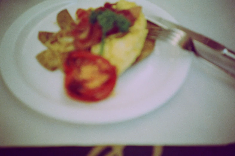 a white plate with a breakfast food with tomatoes and toast