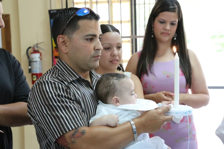 an adult holding a baby while other adults look on