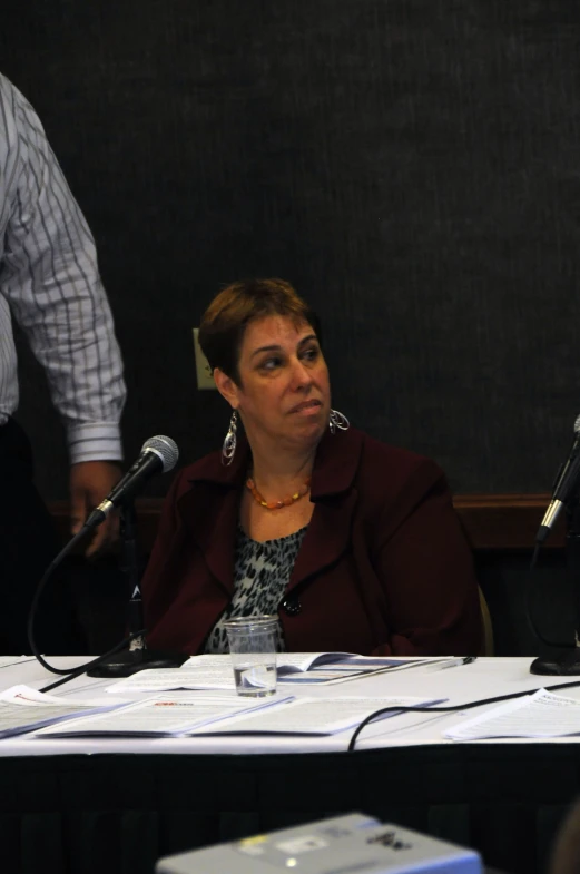 a woman is sitting at a table while two men look on