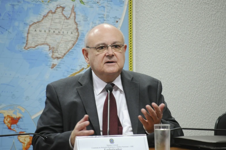 a man with glasses is talking at a table