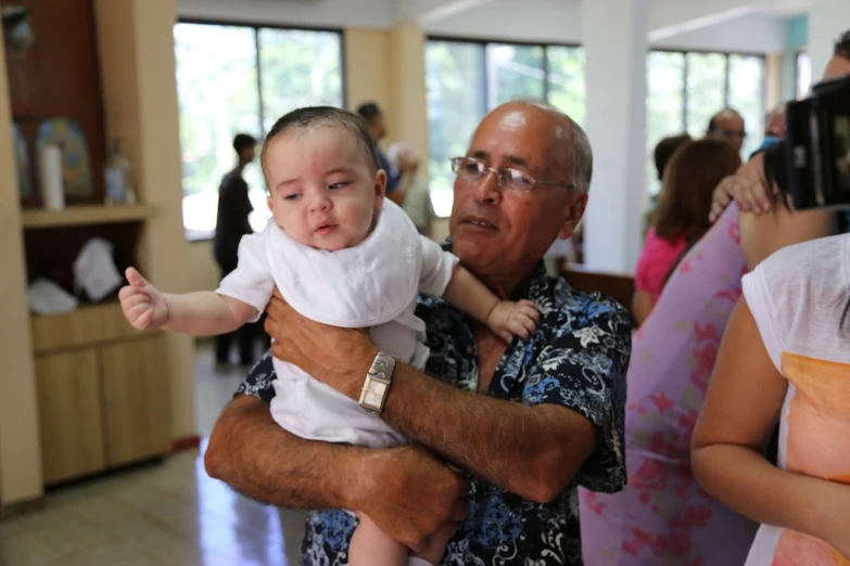 an old man is holding a baby in his arms