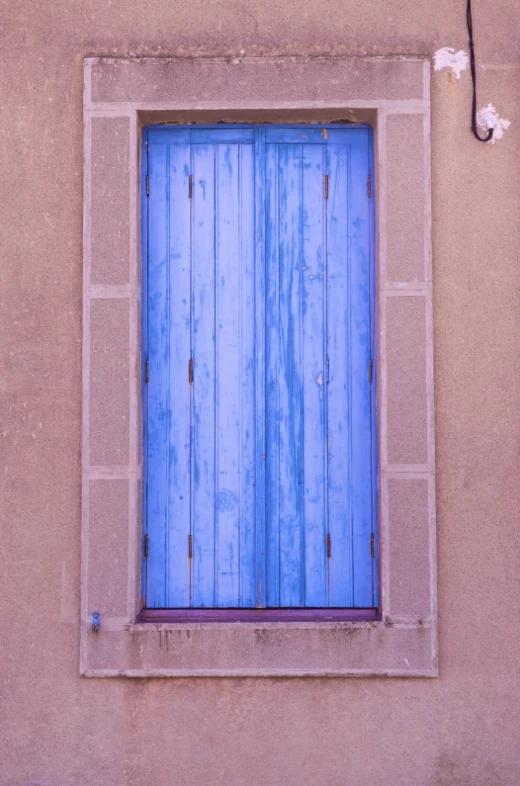 a window with a blue wooden frame in front of a beige wall