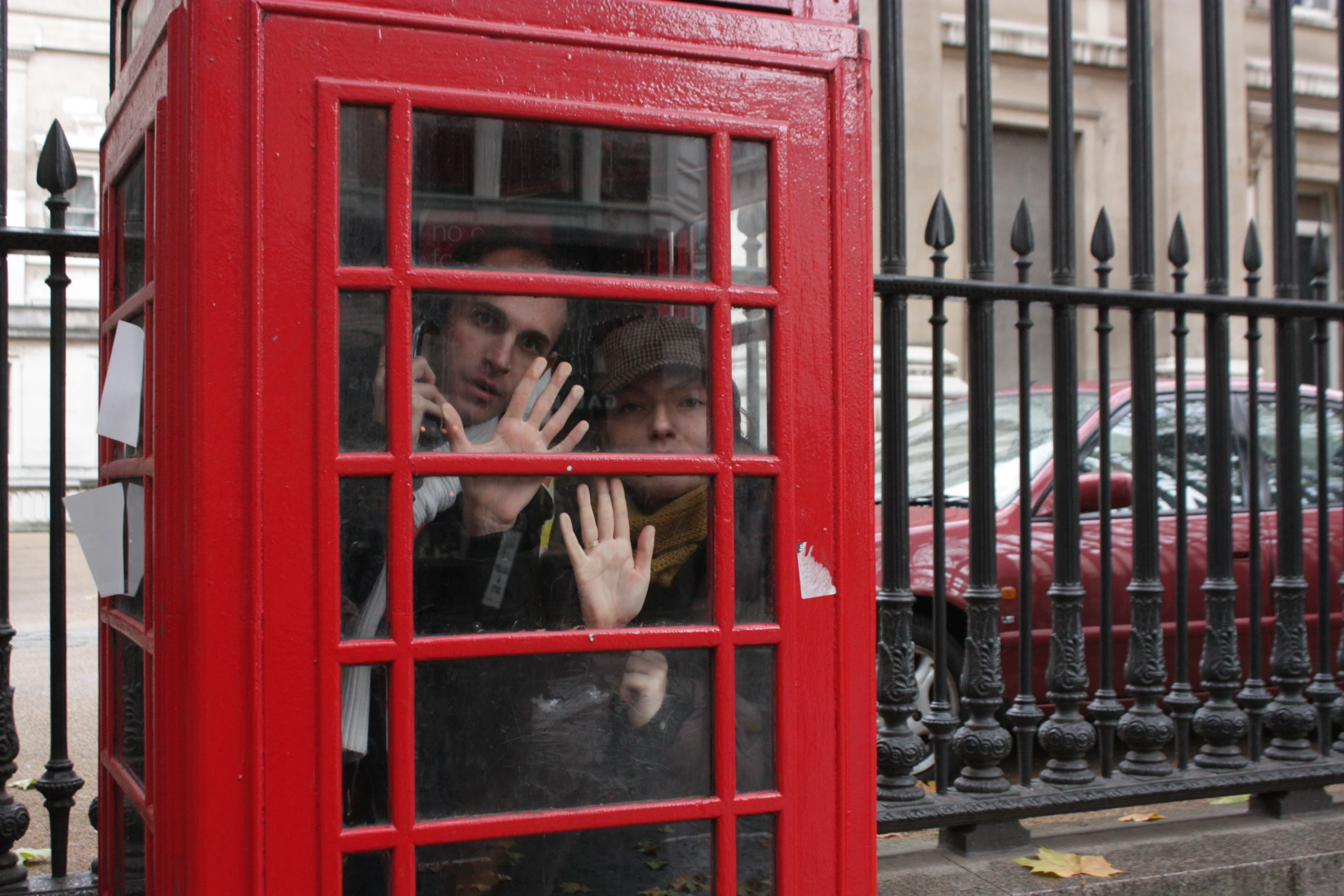 a man and a woman are inside a red telephone booth