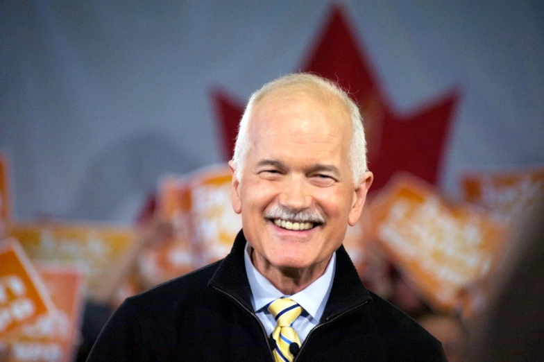 a smiling man in jacket and tie looking ahead