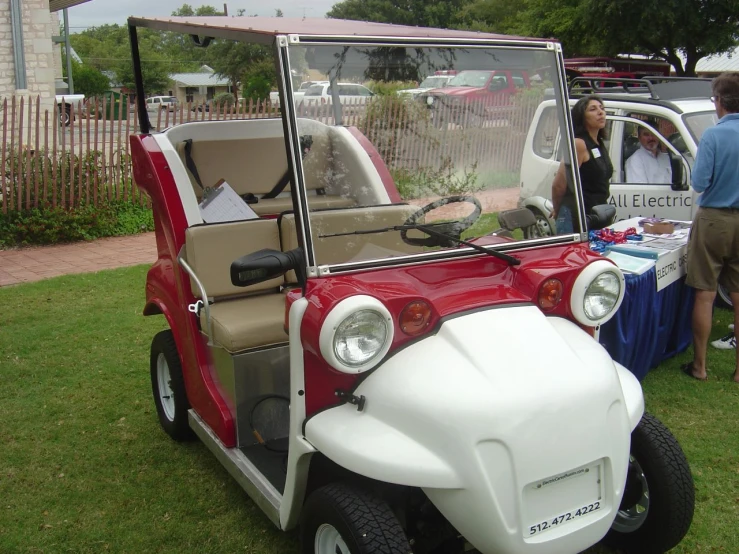 two people stand near two golf carts at a car show