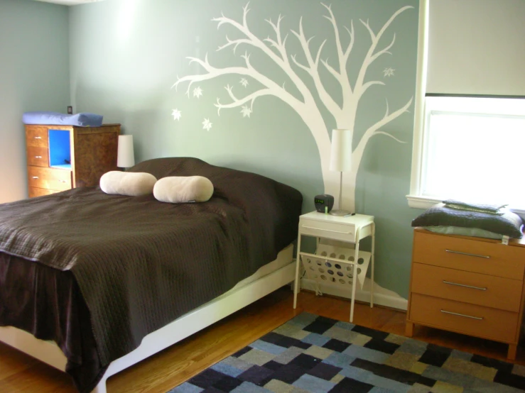 this bedroom has green walls and white tree stencils